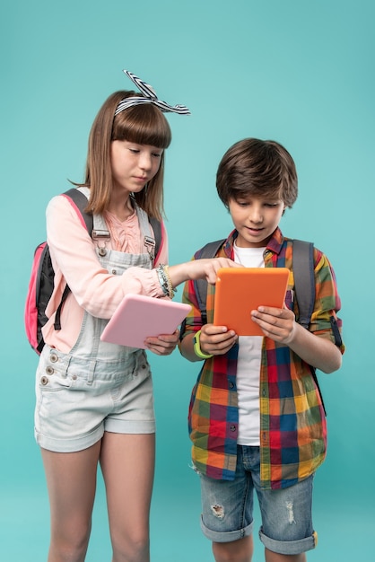 ISTO. Menina bonita determinada segurando seu tablet e consertando o tablet de seus amigos