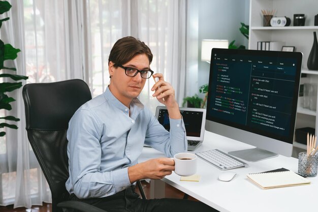 IT-Entwickler sieht aus wie eine Kamera, die eine Kaffeetasse mit Codierung auf einem PC hält Pecuniary