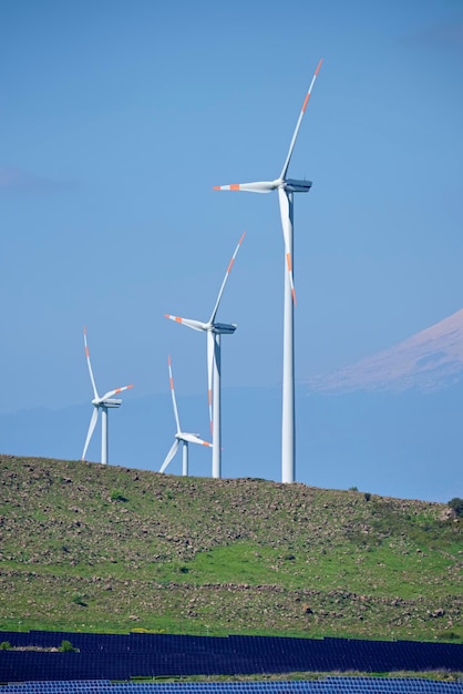 ITÁLIA, Sicília, província de Catania, zona rural; 10 de abril de 2015, turbinas de energia eólica, painéis solares e o vulcão Etna ao fundo - EDITORIAL