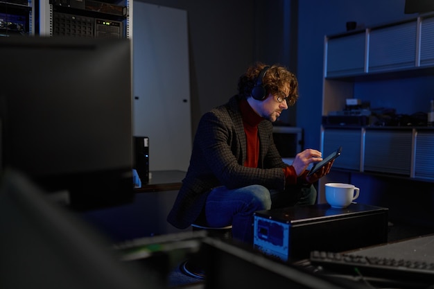 IT-Techniker, der ein digitales Tablet verwendet, während er mit wichtigen Geräten im Rechenzentrum arbeitet. IT-Experte macht Kaffeepause
