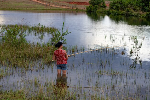 Itaja, Goias, Brasil - 10 15 2021: anciana pescando en un lago con las piernas en el agua