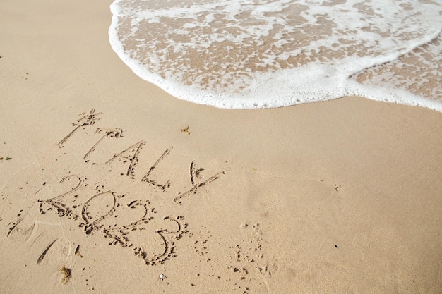 Italia 2023 letras en la playa de arena y agua de mar