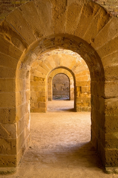 Italia - Antiguo castillo de Siracusa en Sicilia. Arcos de piedra en perspectiva.