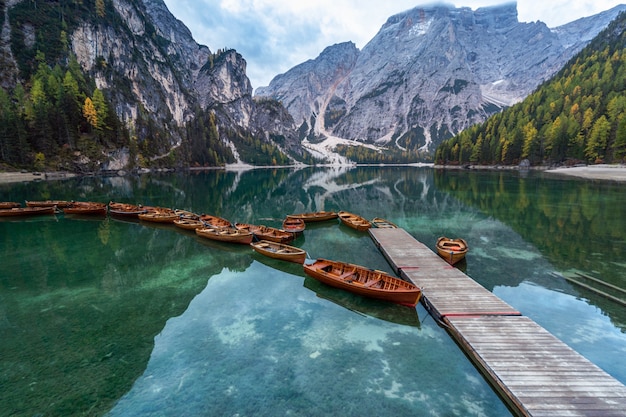 Italia. Montañas Dolomitas y barcos en el lago Braes, paisaje otoñal, vertical.