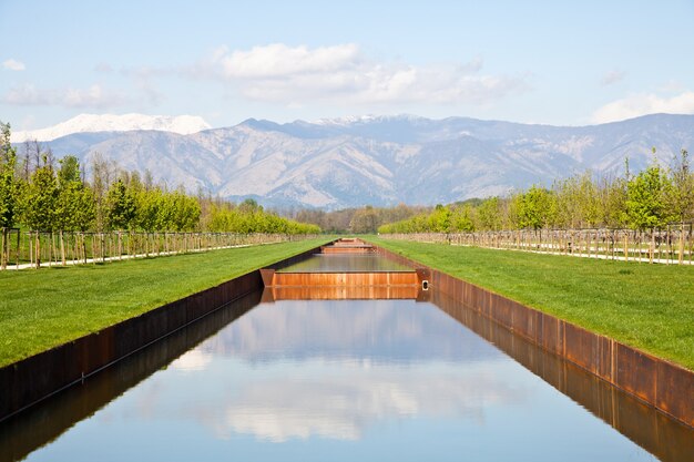 Italia - Piscina de agua en campo verde con montañas de los Alpes en el fondo