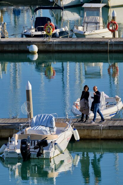 Itália, Sicília, Mar Mediterrâneo, Marina di Ragusa (Província de Ragusa); 4 de fevereiro de 2021, pessoas e barcos a motor no porto - EDITORIAL