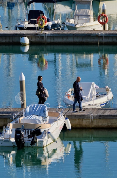 Italia, Sicilia, mar Mediterráneo, Marina di Ragusa (provincia de Ragusa); 4 febrero 2021, personas y embarcaciones a motor en el puerto - EDITORIAL