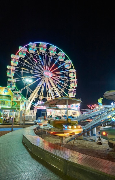 Italia, Sicilia, Marina di Ragusa (provincia de Ragusa), 20 de julio de 2021, vista de un parque de atracciones con carrusel por la noche - EDITORIAL