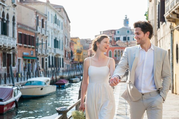 Italia, Venecia, feliz pareja nupcial caminando de la mano en el crepúsculo de la mañana