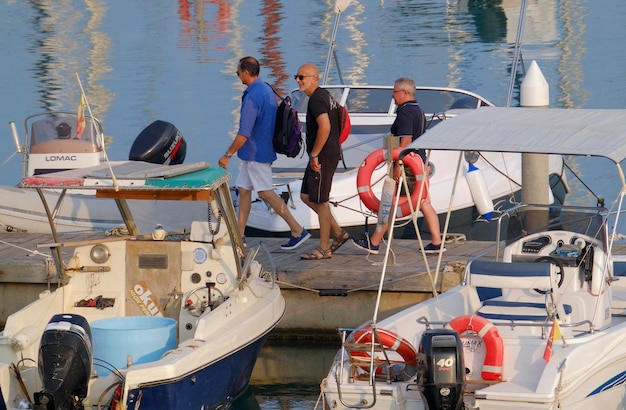Foto italien, sizilien, mittelmeer, marina di ragusa (provinz ragusa); 29. juni 2023, personen, motorboote und luxusyachten im hafen - reditorial