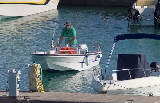 Italien, Sizilien, Mittelmeer, Marina di Ragusa (Provinz Ragusa); 31. Oktober 2020, Fischer auf einem Motorboot im Hafen – EDITORIAL