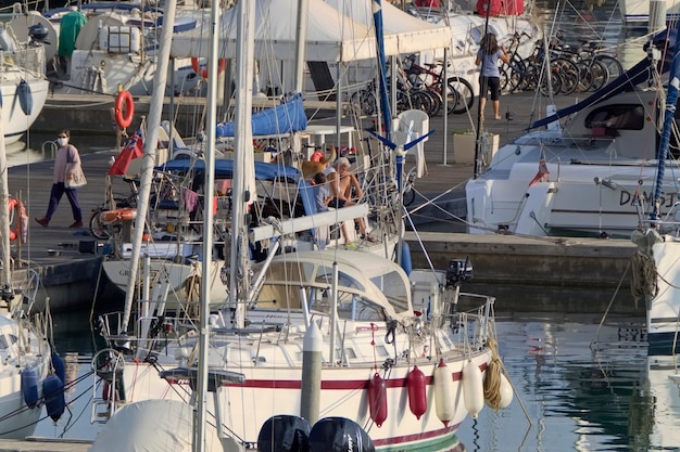 Italien, Sizilien, Mittelmeer, Marina di Ragusa (Provinz Ragusa); 7. November 2020, Menschen mit Hund auf einem Segelboot im Hafen – EDITORIAL