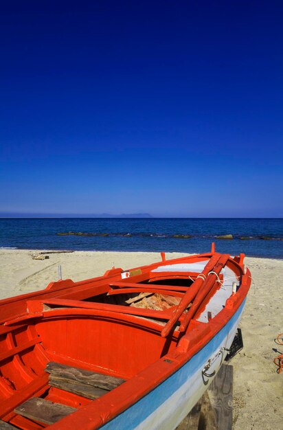 Italien, Sizilien, Tindari, Fischerboot am Strand und die Äolischen Inseln im Hintergrund