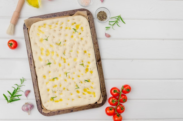 Italienisch keine gebackene Focaccia mit Rosmarin-Knoblauch-Meersalz und Olivenöl auf weißem Holzhintergrund