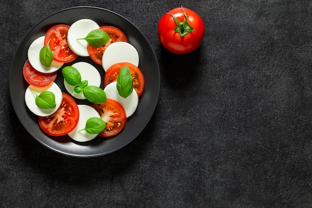 Foto italienische antipasti caprese und ganze tomate auf draufsichtraum des dunklen hintergrundes, zum von textxd zu kopieren