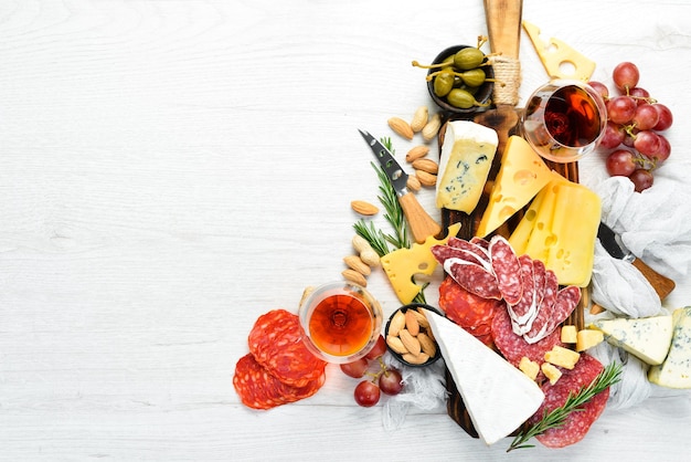 Italienische Antipasti-Wein-Snacks Set Käsesorte Salami und Trauben auf weißem Holzhintergrund Italienische Küche Draufsicht Freier Platz für Ihren Text