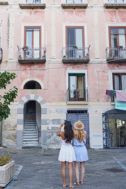 Italienische Architektur ist auf ihre Art schön Ganzkörperaufnahme von zwei nicht wiederzuerkennenden Freunden, die zusammenstehen und mit ihren Handys Fotos in Amalfi machen