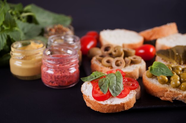 Italienische Bruschetta im Sortiment auf dem Teller, besetzt mit einer kleinen Flasche Senf