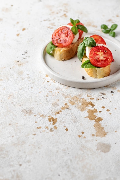 Italienische Bruschetta mit Tomaten, Mozzarella und Basilikum auf weißer Platte mit Textraum