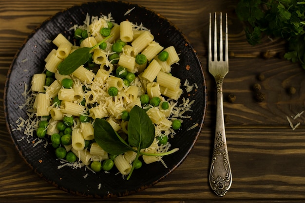 Italienische Ditalini-Nudeln mit Kräutern und Käse, auf einem hölzernen Hintergrund.