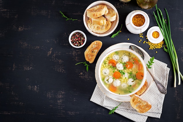 Italienische Fleischklöschensuppe und stelline Teigwaren in der Schüssel auf schwarzer Tabelle.