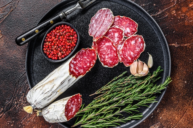 Italienische geschnittene Salami auf einem Teller mit Rosmarin und Thymian.