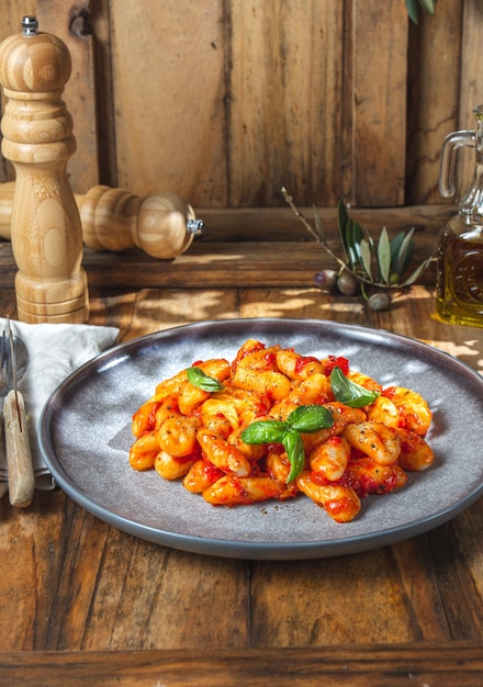 Italienische Gnocchi mit Tomatensauce und Basilikum auf Holzhintergrund