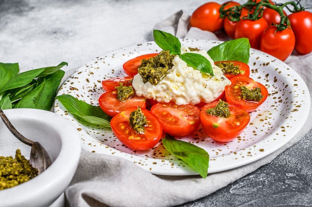 Italienische Käse-Stracciatella (Mozzarella-Büffel) auf kleinem Teller, serviert mit frischen Tomaten und Basilikum.