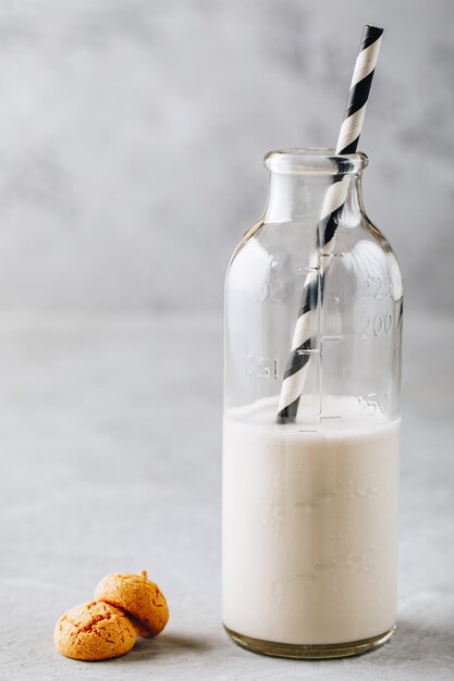 Italienische Keksplätzchen Amaretti mit Milch in einer Glasflasche auf grauem Hintergrund