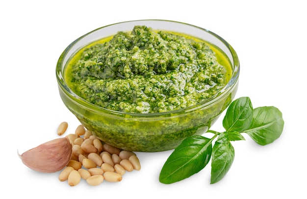 Italienische Kräuter-Pesto-Sauce aus Basilikumblättern, Pinienkernen, Knoblauch und Olivenöl in Glasschüssel auf Weiß