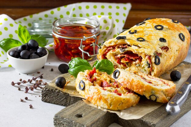 Italienische Kuchenpizza mit Salami, Käse, grünen schwarzen Oliven und sonnengetrockneten Tomaten