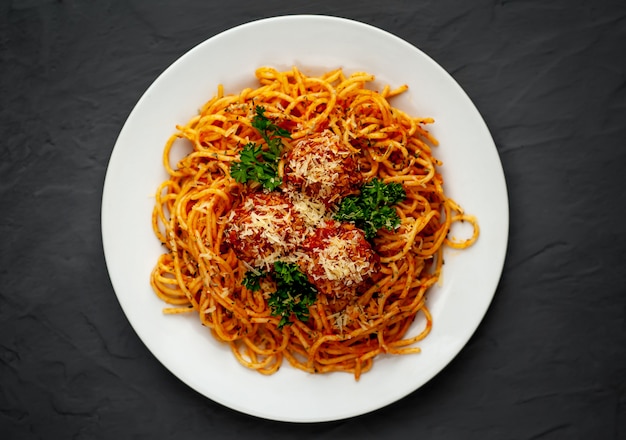 Italienische Nudeln mit Tomatensauce und Fleischbällchen in einem Teller auf einem Steinhintergrund