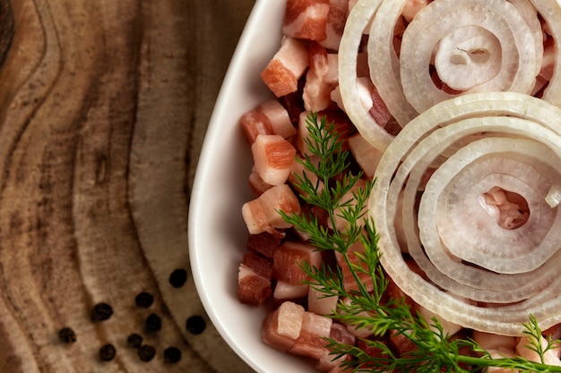 Italienische Pancetta-Speckwürfel aus Schinkenwürfeln in quadratischer weißer Platte