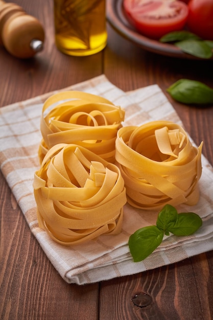 Italienische Pasta-Fettuccine mit Tomaten-Olivenöl-Basilikum auf braunem Hintergrund