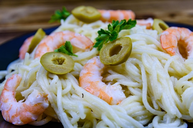 Italienische Pasta mit Garnelen und Oliven in einer schwarzen Platte