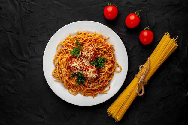 Italienische Pasta mit Tomatensauce und Fleischbällchen in einem Teller mit Gewürzen auf Stein