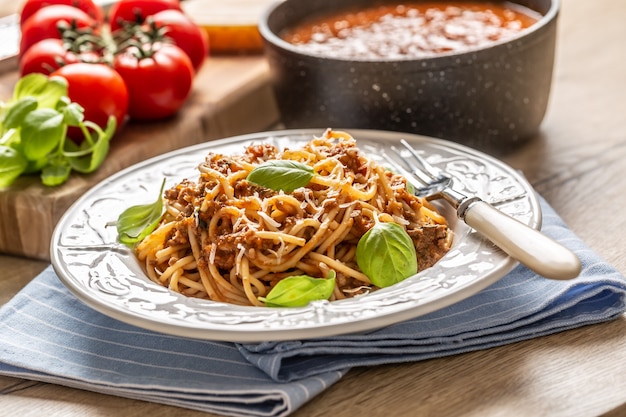 Italienische Pasta Spaghetti Bolognese serviert auf weißem Teller mit Parmesan und Basilikum.