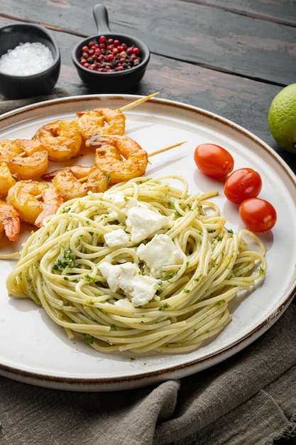 Italienische Pasta Spaghetti mit gegrillten Garnelen, Pesto-Sauce-Set, auf Teller, auf altem dunklem Holztischhintergrund