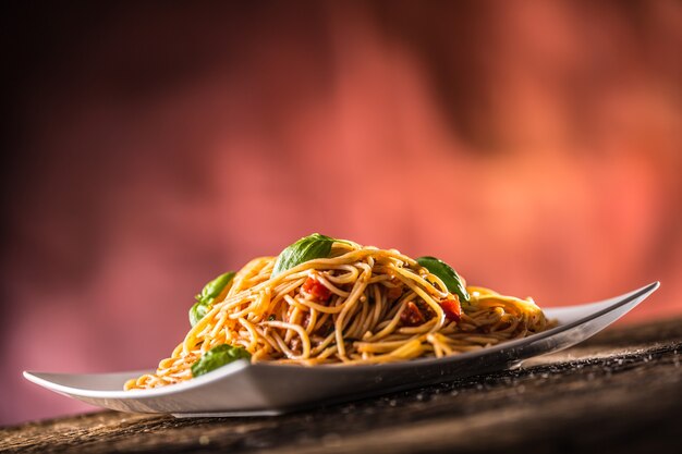 Italienische Pasta Spaghetti mit Tomatensauce Basilikum und Parmesankäse in weißer Platte.