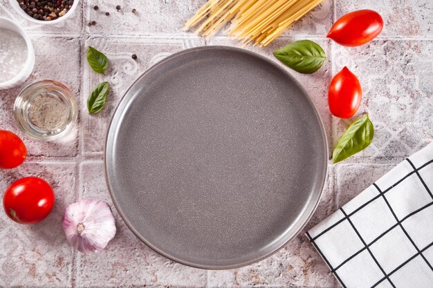 Italienische Pasta-Zutaten auf dem Tisch mit leerem Teller. Essen kochen. Ansicht von oben. Platz kopieren.