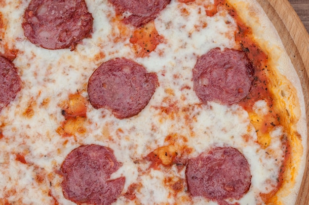 Italienische Pepperonipizza mit Salami auf dunkler hölzerner Draufsicht. Italienisches traditionelles Essen. Beliebtes Street Food