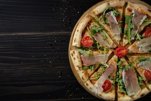 Italienische Pizza mit Baconarugula und Kirschtomaten auf dunklem HintergrundIsolateCopy Space