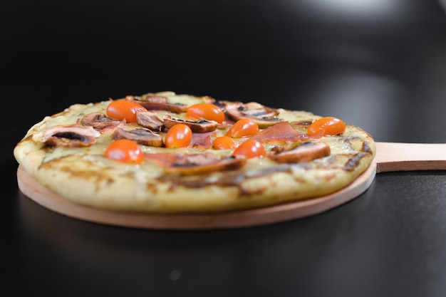 Italienische Pizza mit dünnem Boden, Champignons und kleinen Tomaten und extra Käse