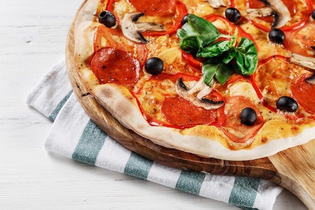 Italienische Pizza mit Pilzen, Basilikum, Tomaten, Oliven und Käse