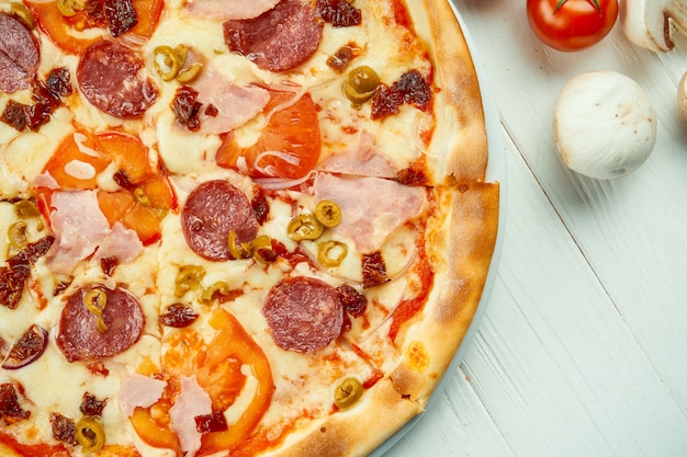 Italienische Pizza mit Salami, Schinken und Oliven in einer Komposition mit Zutaten