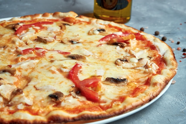 Italienische Pizza mit Speck, Pilzen, Tomaten, geschmolzenem Käse auf grauem Hintergrund. Draufsicht, Essen flach liegen