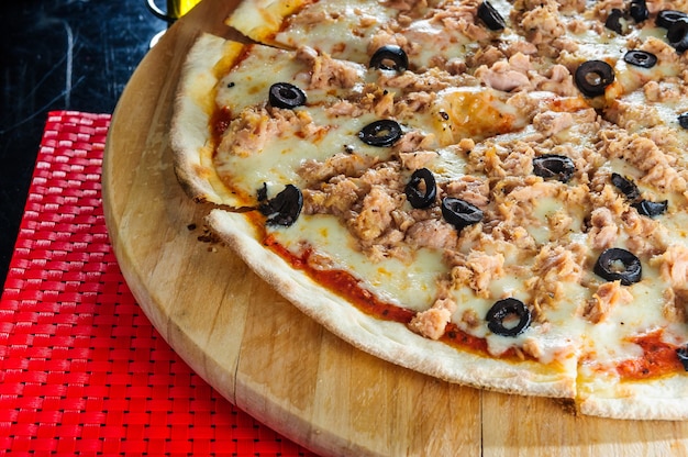 Italienische Pizza mit verschiedenen Fleischsorten und schwarzen Oliven.