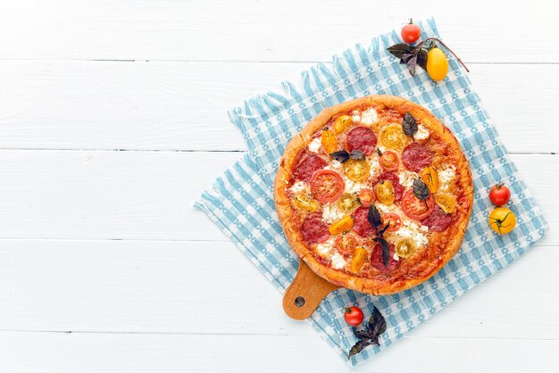 Italienische Pizza Peperoni mit Salami und Käse auf rustikalem hölzernem weißem Hintergrund