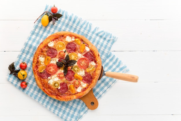 Italienische Pizza Peperoni mit Salami und Käse auf rustikalem hölzernem weißem Hintergrund