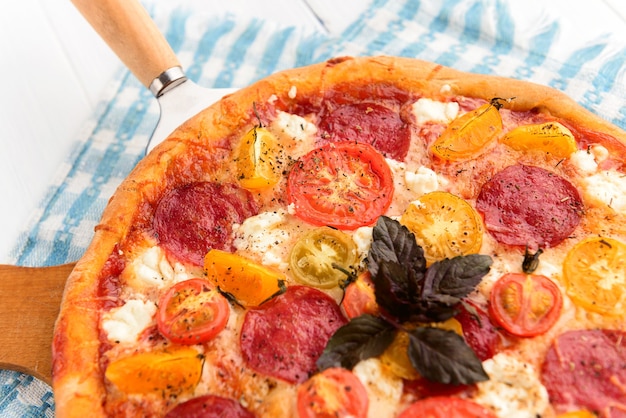 Italienische Pizza Peperoni mit Salami und Käse auf rustikalem hölzernem weißem Hintergrund